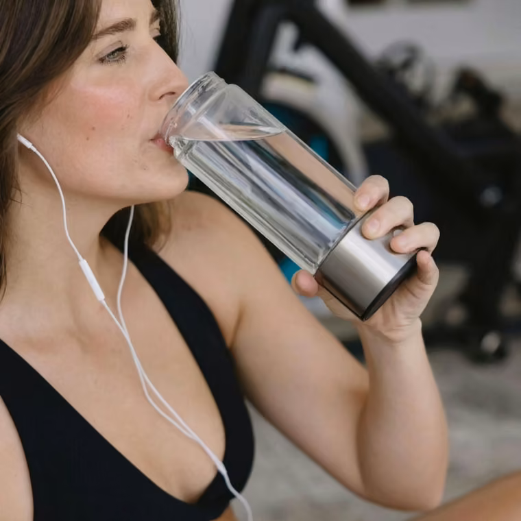 Frau trinkt während ihres Trainings Aquivor Wasserstoffwasser